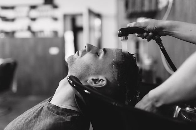 El peluquero lava la cabeza del cliente en la barbería Foto en blanco y negro