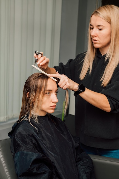 El peluquero levantó un mechón de cabello y cortó la longitud.