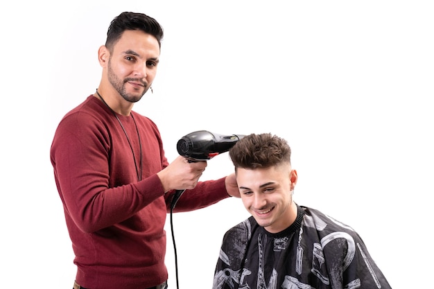 Peluquero masculino secando el cabello a un cliente sobre fondo blanco.