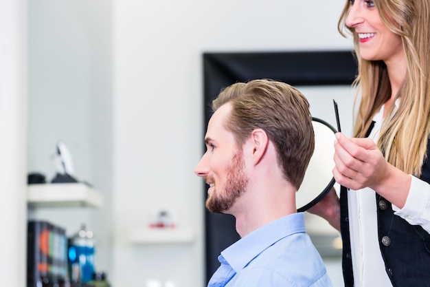 Peluquero mostrando al cliente el nuevo corte.