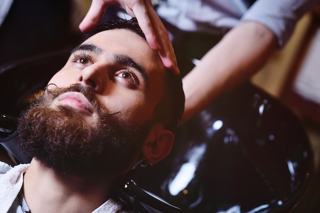 Foto peluquero o peluquero lava la cabeza del cliente