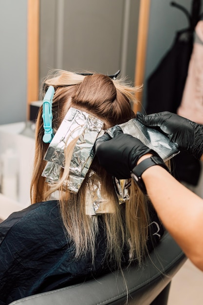 Foto un peluquero profesional aplica tinte al cabello de un cliente coloración del cabello