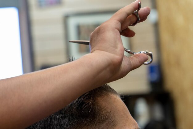 un peluquero profesional corta el cabello de un hombre visita a la peluquería cortar el cabello para el cliente creando un peinado en un salón de belleza corte de cabello masculino en una peluquería
