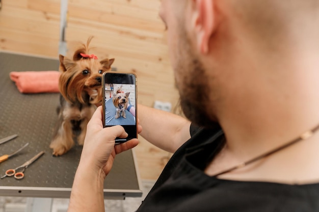 Peluquero profesional masculino haciendo fotos con el cliente del perro después del procedimiento de preparación en el salón de animales