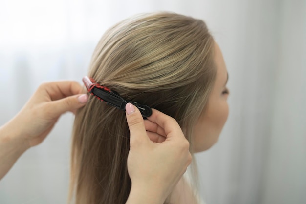 un peluquero profesional pone una horquilla en el cabello de la mujer en el salón