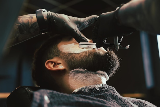 Peluquero profesional que trabaja con un cliente barbudo en el primer plano de la barbería