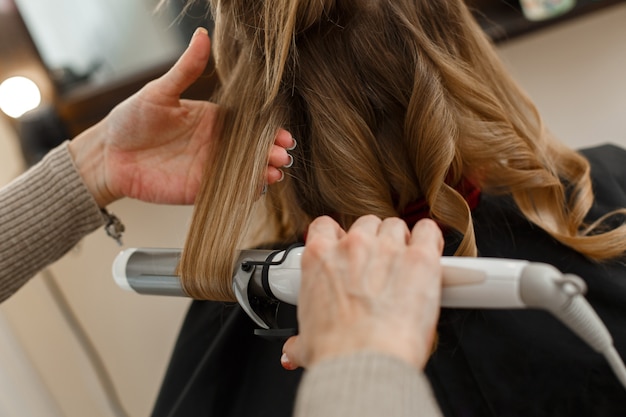 Peluquero profesional que trabaja con el cliente en el salón hairstyle master hace un peinado de noche