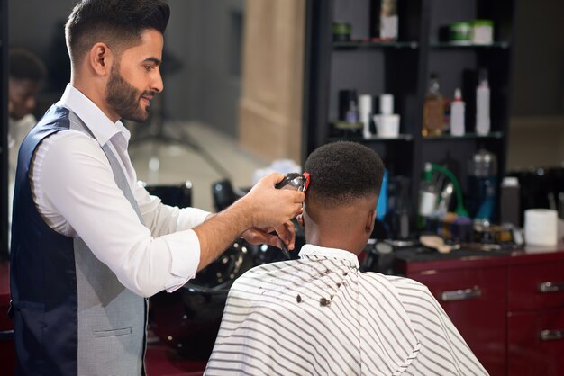 Peluquero recortando el cabello del hombre con podadoras en peluquería