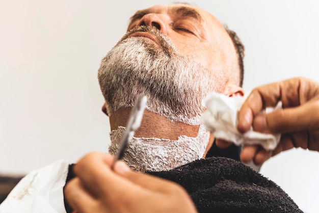 Peluquero recortando y cortando al hombre barbudo con máquina de afeitar en la barbería Proceso de peinado