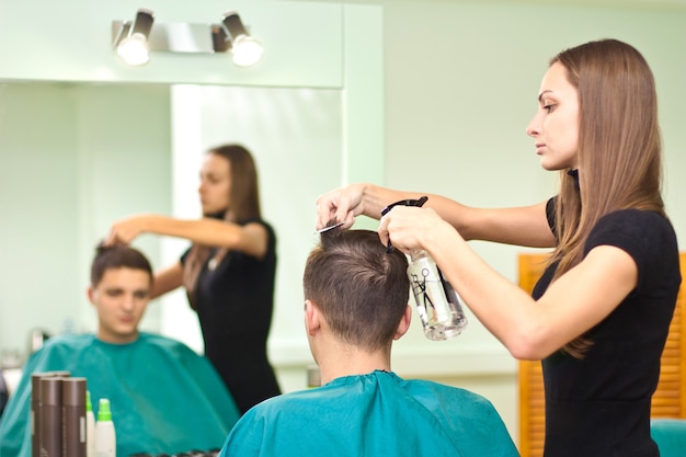 Peluquero seca el cabello del chico en un salón de belleza