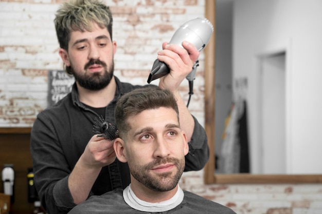 Peluquero secando el cabello del cliente Foto de alta calidad