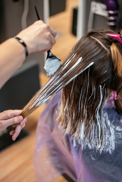 Peluquero teñiendo el cabello de una mujer