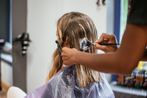 Peluquero teñiendo el cabello de una mujer