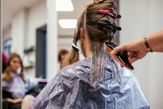 Peluquero teñiendo el cabello de una mujer
