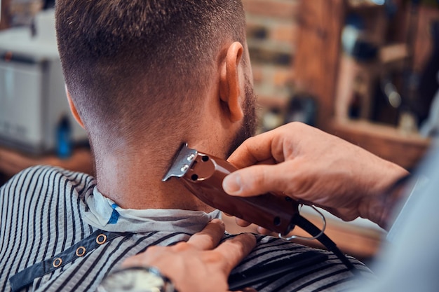 Foto el peluquero thendy en la barbería moderna está trabajando en el corte de pelo del cliente. sesión de fotos de primer plano.