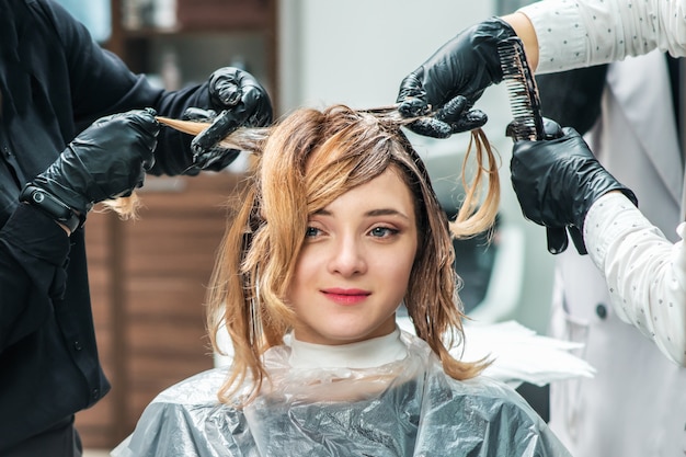 El peluquero se tiñe el cabello femenino.