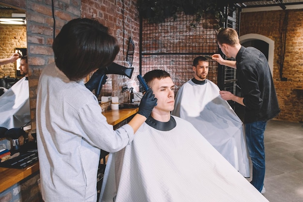 Los peluqueros cortan a sus clientes en peluquería. Concepto de publicidad y peluquería.