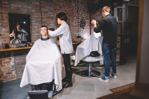 Los peluqueros cortan a sus clientes en peluquería. Concepto de publicidad y peluquería.
