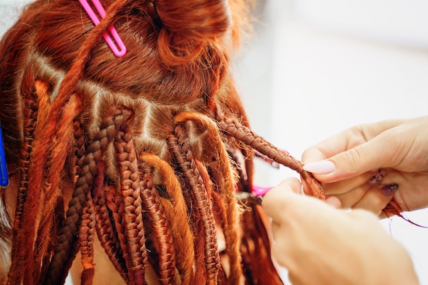 Peluqueros peinado estilo hippie manos trenzas chicas jengibre rastas coletas brillantes en la cabeza