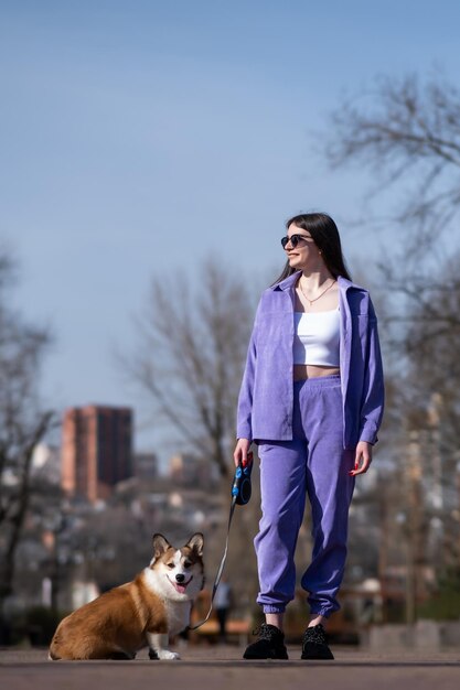 Foto pembroke welsh corgi cachorrinho caminha com seu dono em um dia ensolarado em um parque da cidade de pé ao lado do dono cão feliz conceito de cuidado vida animal saúde show raça de cão