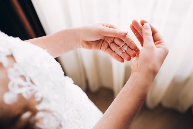 Pendientes de dama de honor. Niña sostiene un pendiente. gentil mañana de la novia. publicidad de joyas