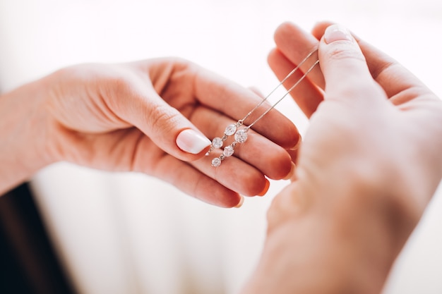 Pendientes de dama de honor. Niña sostiene un pendiente. gentil mañana de la novia. publicidad de joyas