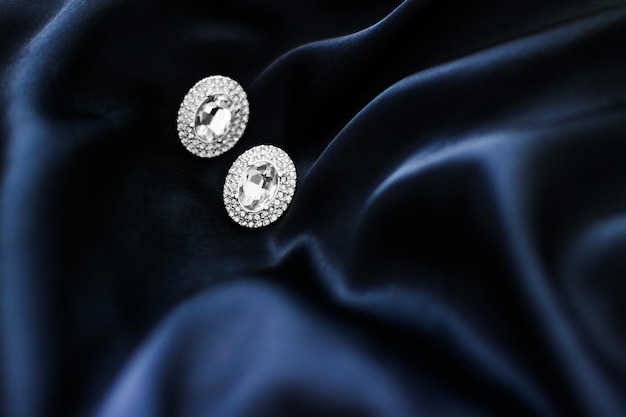 Pendientes de diamantes de lujo sobre fondo de seda azul oscuro joyas de glamour de vacaciones presentes