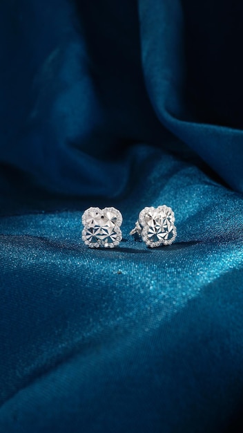 Pendientes de diamantes de oro blanco aislado sobre fondo azul.