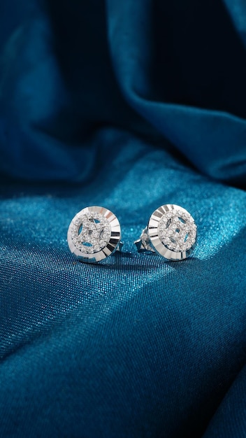 Pendientes de diamantes de oro blanco aislado sobre fondo azul.