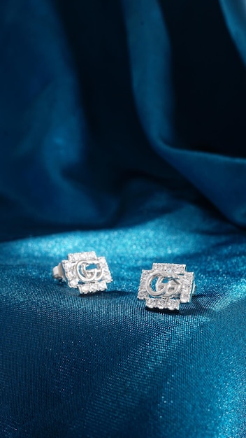 Pendientes de diamantes de oro blanco aislado sobre fondo azul.