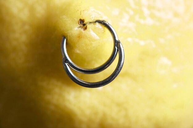 Pendientes piercing en un limón sobre un fondo.