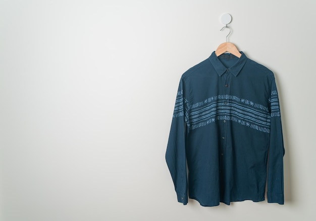 pendurando a camisa da marinha com cabide de madeira na parede