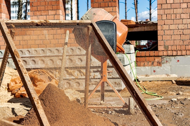 Peneirar areia para argamassa no canteiro de obras Purificação de areia de impurezas para a preparação de argamassa para alvenaria ou reboco de paredes