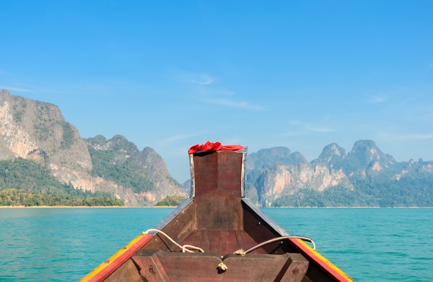 Penhasco da montanha da pedra calcária com o barco de cauda longa na província de Surat Thani, Tailândia