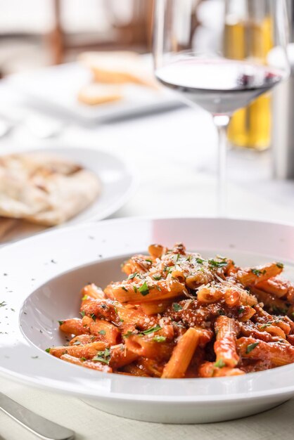 Penne alla arrabiata servido com vinho branco em ambiente de restaurante