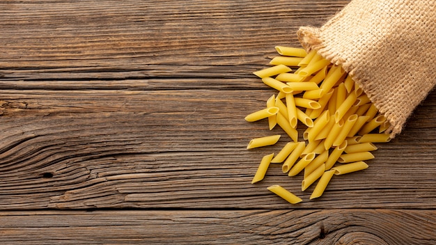 Penne crudo en mesa de madera con espacio de copia