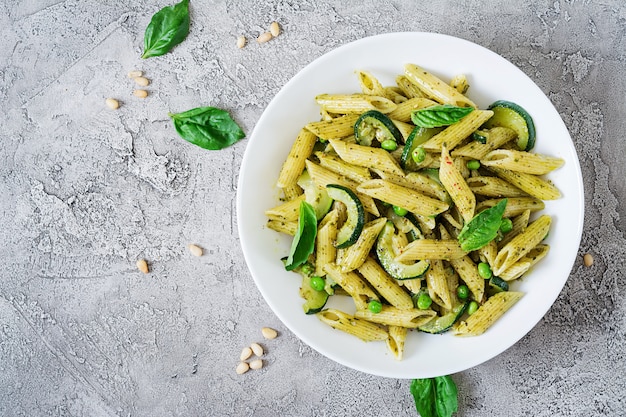 Penne-Nudeln mit Pesto-Sauce, Zucchini, Erbsen und Basilikum. Italienisches Essen.