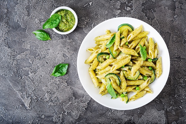 Penne-Nudeln mit Pesto-Sauce, Zucchini, Erbsen und Basilikum. Italienisches Essen.