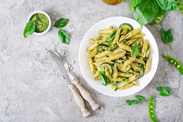 Penne Nudeln mit Pesto-Sauce, Zucchini, Erbsen und Basilikum. Italienisches Essen.