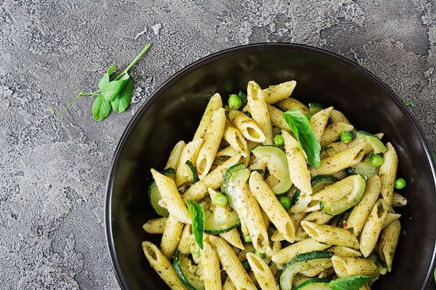 Penne Nudeln mit Pesto-Sauce, Zucchini, Erbsen und Basilikum. Italienisches Essen.