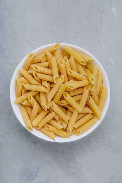 Penne-Nudeln Rohe italienische Penne-Nudeln auf grauem Steinhintergrund