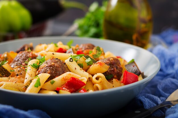 Penne pasta con albóndigas en salsa de tomate y verduras en un tazón