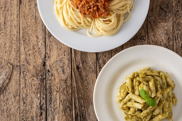 Penne pasta y espaguetis con platos de salsa boloñesa en mesa de madera