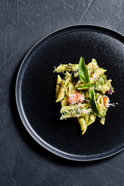 Penne pasta italiana con espinacas, tomates cherry y albahaca. Ingredientes para cocinar.