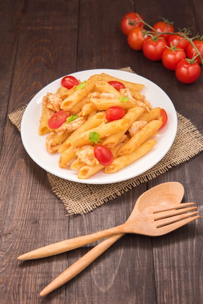 Penne pasta en salsa de tomate con pollo en una mesa de madera