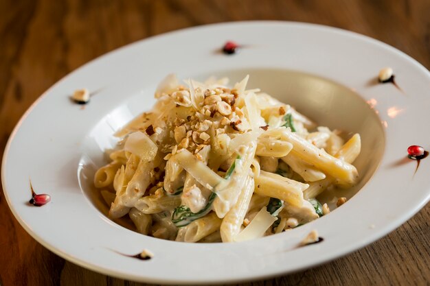 Penne con pollo, espinacas y avellanas en salsa de parmesano