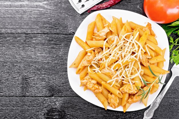 Penne con pollo y tomate en plato a bordo