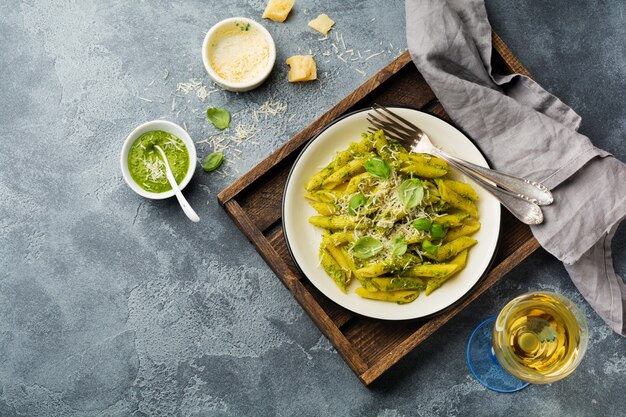 Penne Rigate Pasta mit Parmesan und Basilikumblättern in Keramikplatte auf grauem Vintage alten Betontisch.