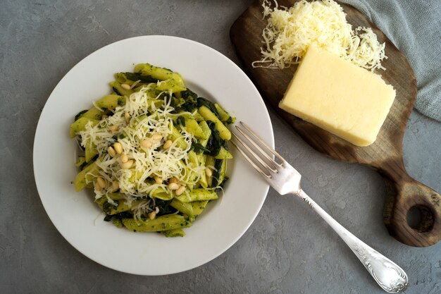 Penne-Teigwaren mit Spinat auf grauem Hintergrund.