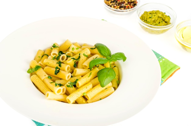 Penne-Teigwaren mit Spinatbasilikum-Pestosoße auf weißer Platte.